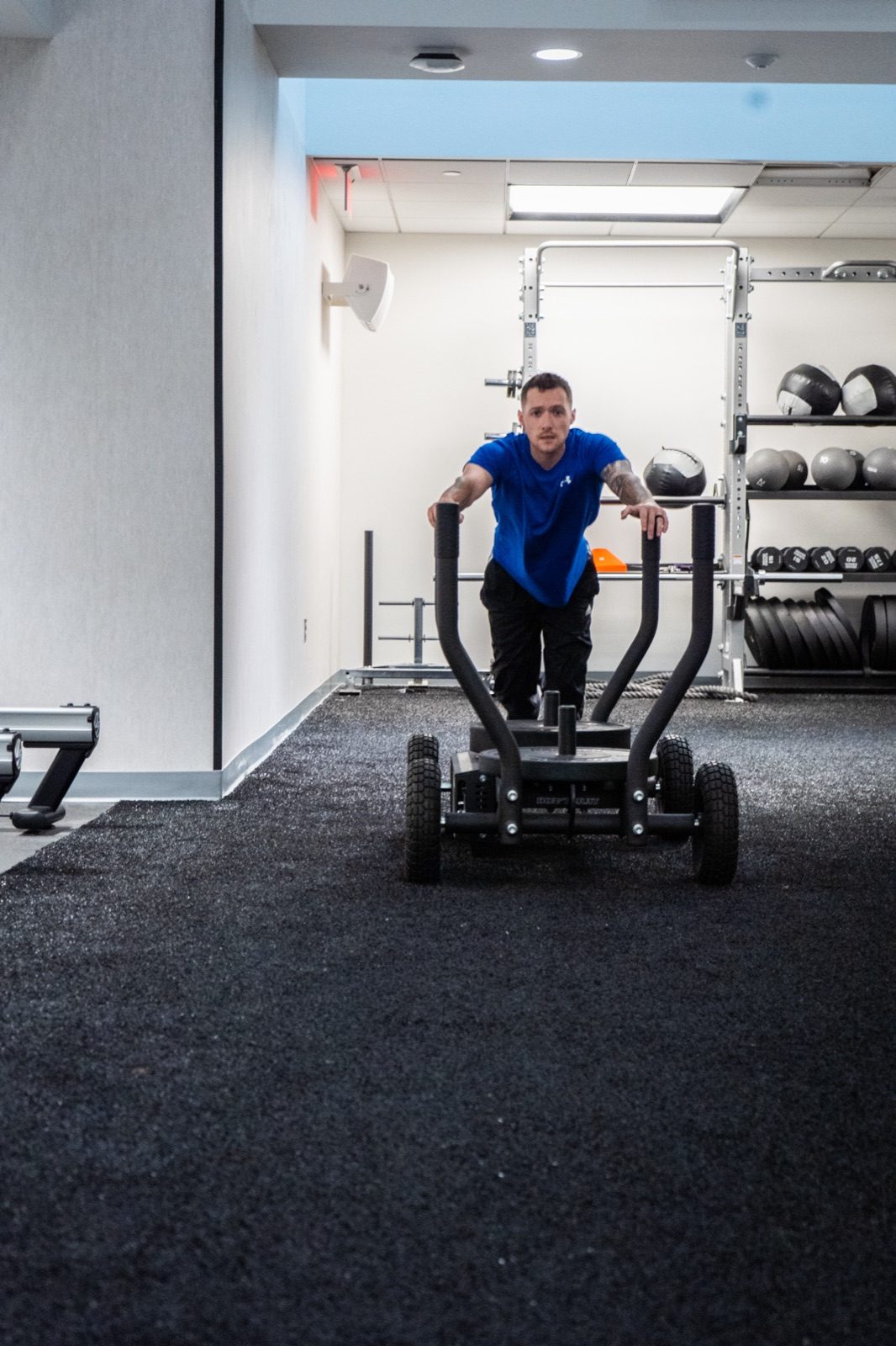 A certified First Fitness Management trainer pushing a sled during a workout